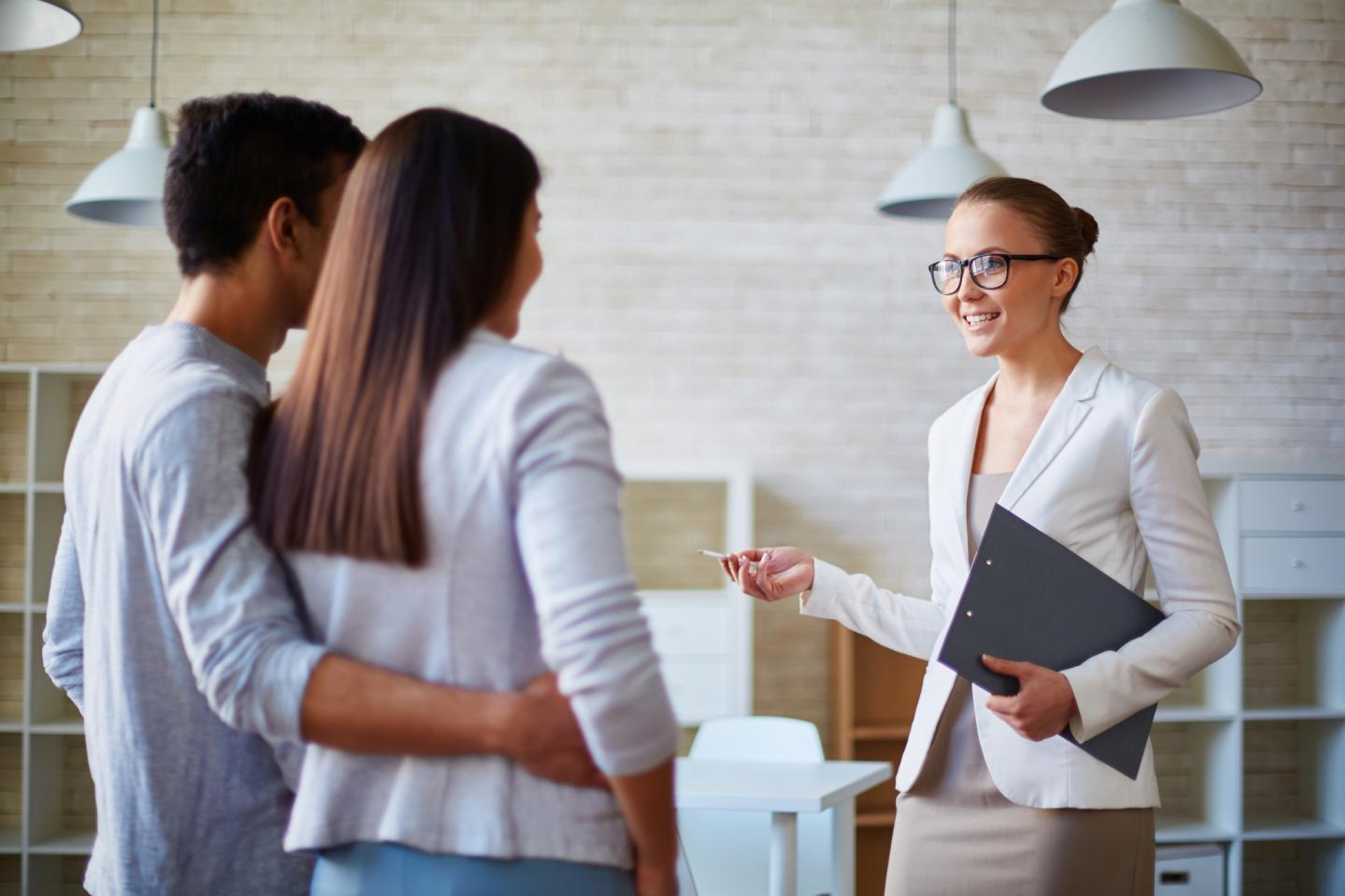 A female realtor walking a couple through an open house